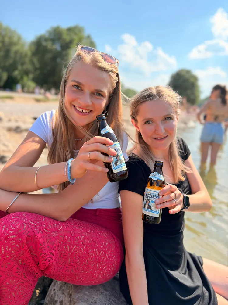 Zwei Freundinnen stoßen mit Maxl an der Isar an